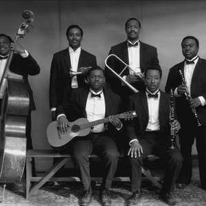 BOLDEN, BUDDY BOLDEN'S BAND, LEFT TO RIGHT: KOREY WEBB-TURNER (BASS), GARY CARR (AS BUDDY BOLDEN), DONALD WATKINS (GUITAR), SER'DARIUS BLAIN (TROMBONE), CALVIN JOHNSON (CLARINET, SEATED), BREON PUGH (CLARINET), 2019. © ABRAMORAMA
