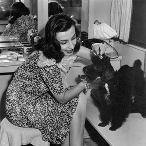DAYS OF GLORY, Tamara Toumanova, grooming her French poodle, Bela, on-set, 1944