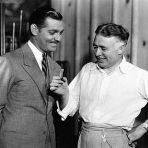 CHAINED, director Clarence Brown (right) shows Clark Gable the tail of the rattlesnake he shot on the front lawn of his home on set, 1934