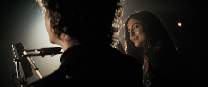 Bob Dylan (Timothée Chalamet) and Joan Baez (Monica Barbaro) play a concert together, in "A Complete Unknown." (Searchlight Pictures)