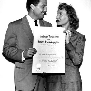 Robert Stack, left, receiving a Best Actor award for his role in WRITTEN ON THE WIND, from Screen Stars Magazine editor Bessie Little, 1956