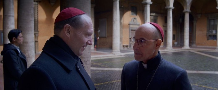 Cardinal Lawrence (Ralph Fiennes, L) and Cardinal Bellini (Stanley Tucci) speak in the Cortile della Pigna, in "Conclave." (Focus Features)