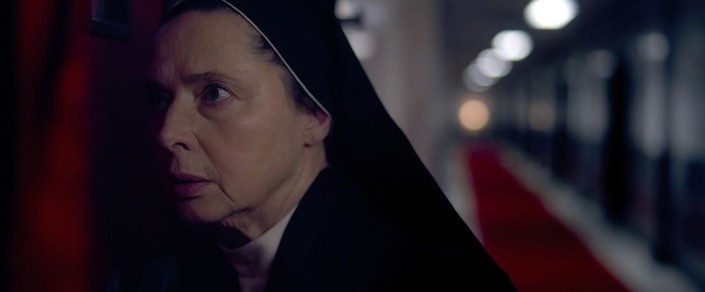 Sister Agnes (Isabella Rossellini) eavesdrops on whoever has broken the seal of the former pope's quarters and is apparently snooping about, in "Conclave." (Focus Features)