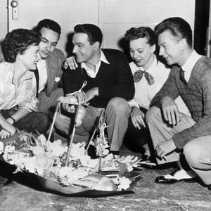 SINGIN' IN THE RAIN, Assistant directors Jeanne Coyne (left) and Carol Haney (second from right) present directors Stanley Donen and Gene Kelly, Donald O'Connor with first day of shooting gifts in inverted umbrellas, 1952