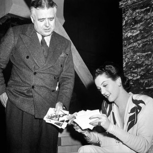 THEY MET IN BOMBAY, director Clarence Brown, Rosalind Russell looking at photographs on set, 1941
