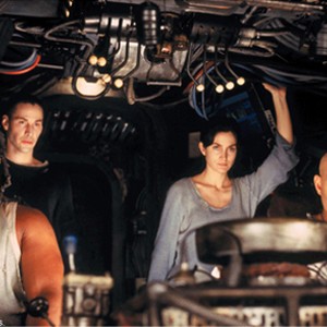 Anthony Ray Parker as Dozer, Keanu Reeves as Thomas A. Anderson/Neo, Carrie-Anne Moss as Trinity, and Laurence Fishburne as Morpheus in Nebuchadnezzer's cockpit.