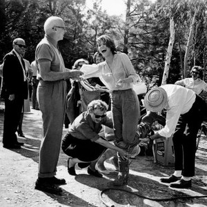 MAN'S FAVORITE SPORT?, director Howard Hawks (holding script) laughs along with Paula Prentiss as she is being dried off after accidently falling into the lake on set, 1964