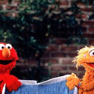 Elmo (left) goes on an adventure to find his cherished blue blanket when it gets lost in Grouchland during a game of tug-of-war with his friend Zoe.