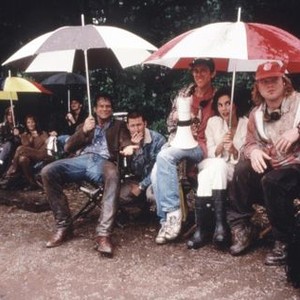 TWISTER, Bill Paxton (holding black and white umbrella), Todd field (smoking), Jami Gertz (holding red and white umbrella), Philip Seymour Hoffman (red cap) on set, 1996, © Warner Brothers