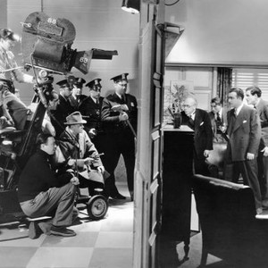 KING OF GAMBLERS, director Robert Florey (foreground left) directing fourth take of scene where policemen smash down doors, right side of door: Barlowe Borland, Paul Fix, Akim Tamiroff, Colin Tapley, during filming, 1937