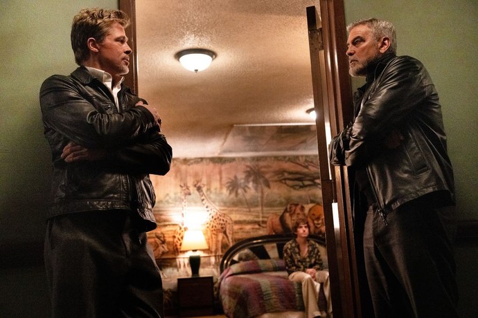 Pam's Man (Brad Pitt, L) and Margaret's Man (George Clooney) decide what to do about The Kid (Austin Abrams, on bed), in "Wolfs." (Apple Original Films)