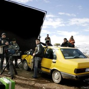 IKLIMLER, (aka CLIMATES, aka THE CLIMATE), cinematographer Gokhan Tiryaki (standing behind camera, in white and blue parka), writer/director/actor Nuri Bilge Ceylan (second from right, behind car), on set, 2006, ©Zeitgeist Films
