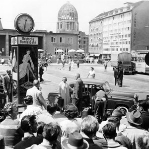 INTERLUDE, director Douglas Sirk (beneath clock), June Allyson (in front of car), filming a scene outside railway station in Munich, Germany, 1957