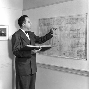 H.M. PULHAM, ESQ., director King Vidor checks the blueprint for the office set, 1941